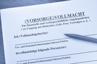 Nahaufnahme eines Formulars für eine Vorsorgevollmacht, mit Kugelschreiber auf Holzuntergrund.