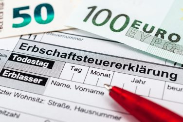 Erbschaftsteuerformular mit Euro-Scheinen und einem roten Stift.
