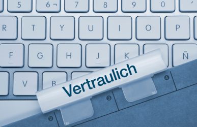 Tastatur mit blauen Akzent. Dokument mit Aufschrift "Vertraulich" liegt obenauf.