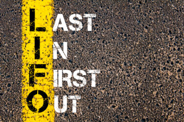 Buchstaben "LIFO" auf gelbem Streifen, darüber "Last In First Out" auf Asphalt.