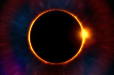 Sonnenfinsternis mit leuchtendem Sonnenring und farbigem Hintergrund am Nachthimmel.