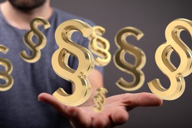 Golden paragraph symbols hover over a hand, representing legal concepts, law, and regulations.